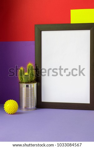 Black empty frame with white copy space on the ultra violet red yellow 2x3 vertical background and yellow cactus in metal can and yellow pimply ball  Diagonal  Royalty-Free Stock Photo #1033084567