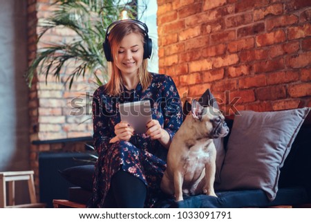 Portrait of a happy charming blonde with the tablet and headphon