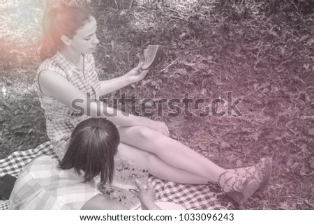 Two young women enjoying  conversation and eating watermelon on picnic outdoors