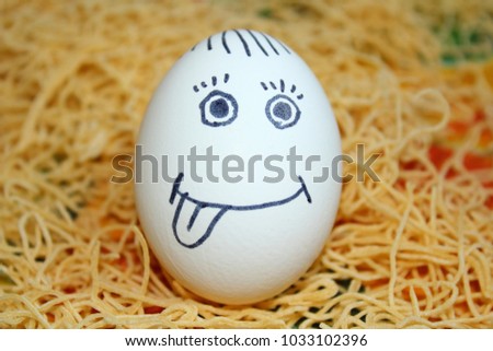 Chicken egg with painted face standing on homemade noodles. Close-up.