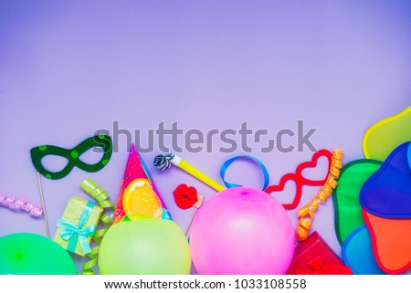 Top view bright party tools and decoration - baloons, funny carnival masks, festive tinsel on lilac background. Happy birthday greeting card. Purim. Design concept. Select focus, place for text.