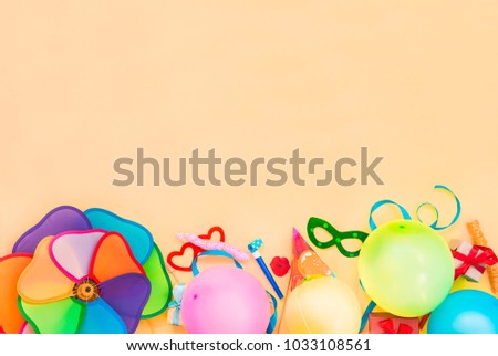 Top view bright party tools and decoration - baloons, funny carnival masks, festive tinsel on peach color background. Happy birthday greeting card. Design concept. Select focus, place for text.