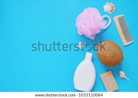 Flat lay beauty mock up. Pink bath sponge, white shampoo bottle, wooden hair brush, handmade soap bar and seashells on a blue background. Cosmetic products with natural organic ingredients