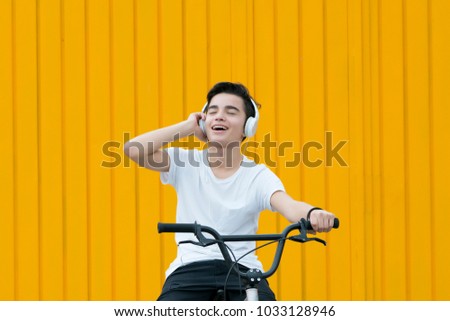 Young boy listens to music with headphones on a bicycle.