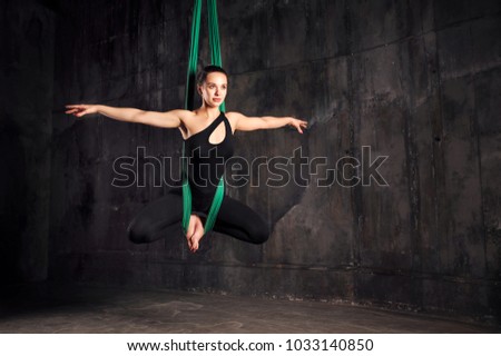 Young woman doing fly yoga stretching exercises in fitness training gym loft classroom. Sport and healthy lifestyle concept. Copy space.
