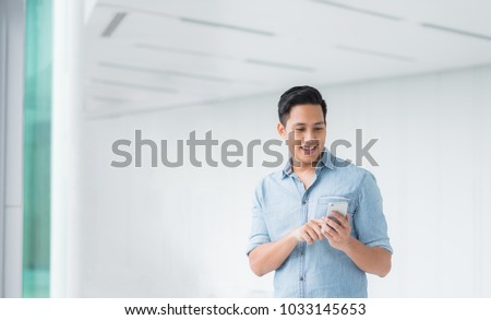 Happy Asian man using smartphone mobile in modern building  Royalty-Free Stock Photo #1033145653