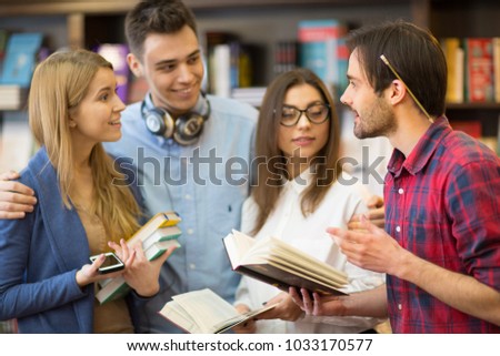 Young handsome bearded man talking to his friends while studying together at the college library campus university high school education teenagers communication inspiring learning.