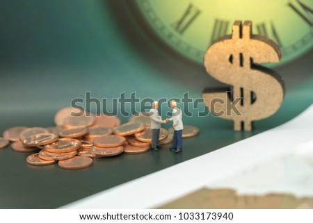 Miniature people: Business man hand shake and stack of coins, wooden dollar with copy space using as background sale, buy, trade, deal, business time concept.