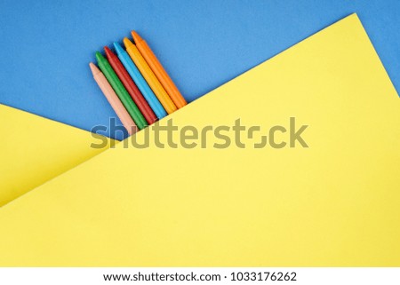 Creative composition of colored pencils on a yellow and blue paper background