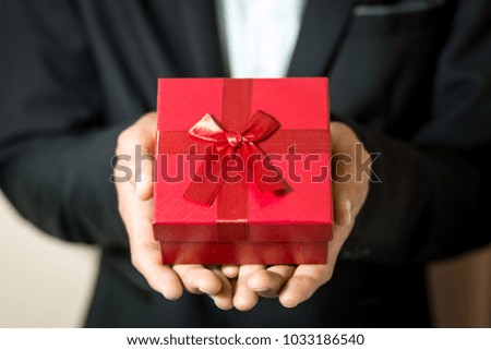 Business man hold red gift box in hands.