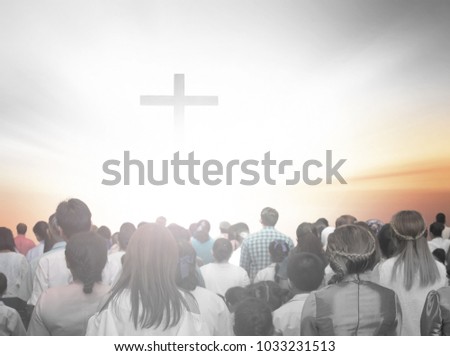 soft focus of christian people group raise hands up worship God Jesus Christ together in church revival meeting with image of wooden cross over cloudy sky can be used for Christian worship background