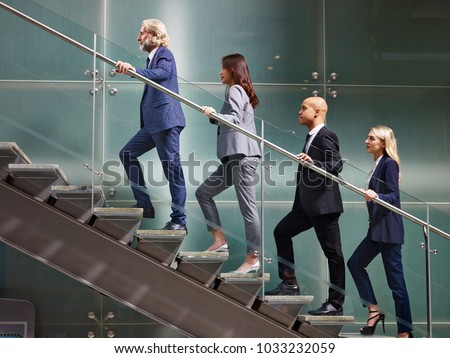 multinational and multiethnic corporate business people male and female walking up stairs in a line in modern office building. Royalty-Free Stock Photo #1033232059
