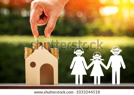 Woman hand holding a coin save in the wooden house and a family with paper art in the public park, Saving money or loan for business investment real estate of owner and buy a new home concept.