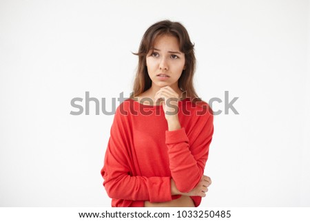 Picture of upset brunette student girl of mixed race appearance having worried look, holding hand on her chin, feeling nervous before exams at college. Stress, anxiety, worry and emotions concept