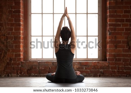 Young sporty woman practicing yoga, doing Sukhasana exercise, Easy Seat pose, working out, wearing sportswear, black pants and top, indoor full length, yoga studio window, rear view Royalty-Free Stock Photo #1033273846