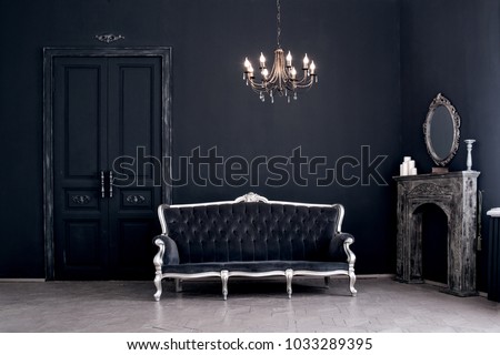Black room in the castle with a vintage door, a chandelier, a sofa  and amirror and fireplace. Space where you can mount a person. Royalty-Free Stock Photo #1033289395