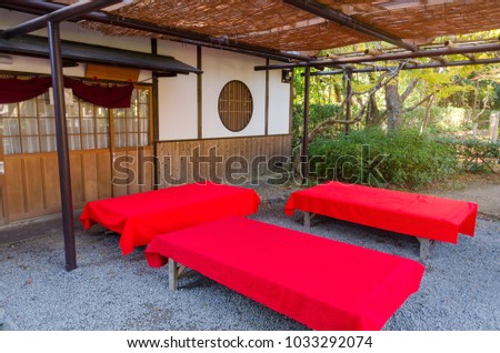 wooden bench with red cover in traditional Japanese garden with autumn leaves colors in Kyoto, Japan