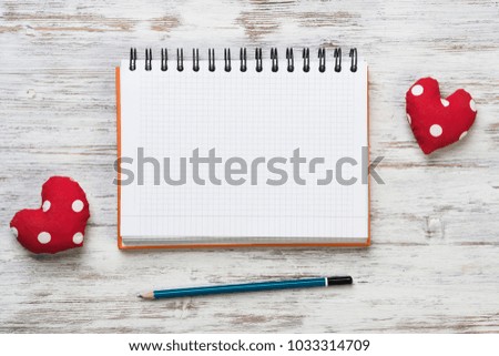 Hearts and blank notepad with pencil on wooden table