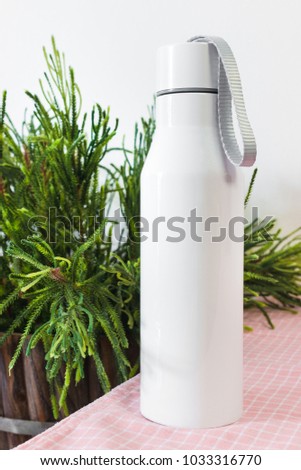 Steel bottle with rope on kitchen table background. Blank drink container for design.