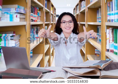 Picture of female high school student showing thumbs up while studying in the library