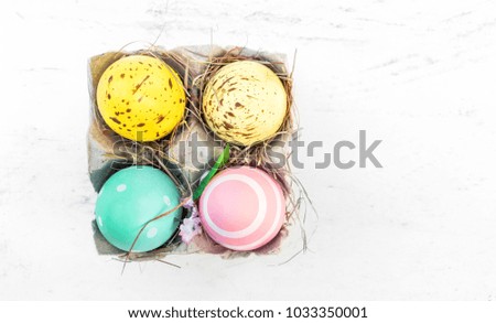 Easter eggs in egg cartoon box on white rustic wooden table with copy space. Festive decorations. Happy Easter!
