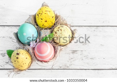 Easter eggs in egg cartoon box on white rustic wooden background close up. Festive decorations. Happy Easter!
