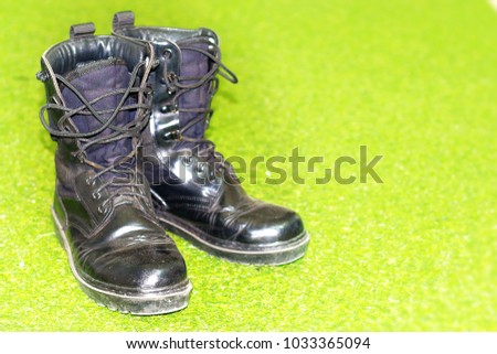 black combat boots for soldier in army on green grass background 