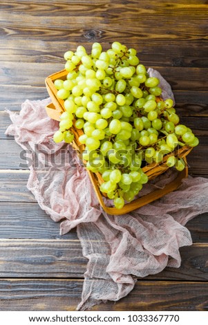 Image from above of green grapes in wooden box with pink cloth