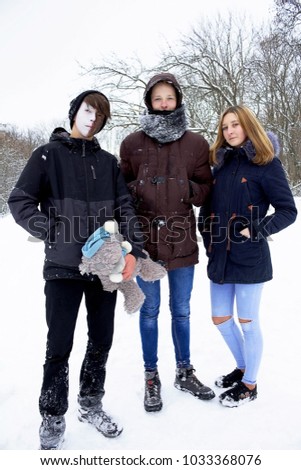 The girl stands alone between the two guys, holding them under her arms.