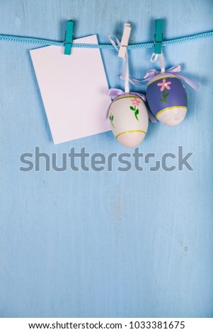 Easter Eggs and paper on a rope on a blue wooden background.  Easter still life can be used as a postcard.