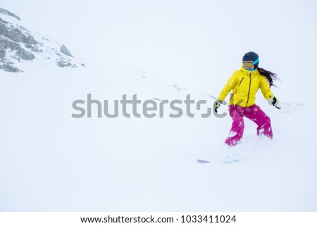 Photo of female athlete wearing helmet with developing hair, snowboarding from mountain slope
