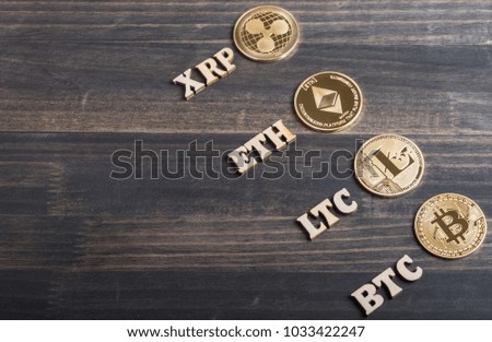 Popular cryptocurrency bitcoin, litecoin, ripplecoin and ethereum with text on wooden background.