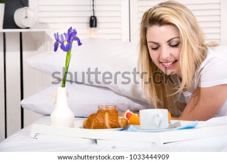 Beautiful young woman having breakfast in bed. Surprise from beloved husband. Celebrating a woman's day, mother's day.