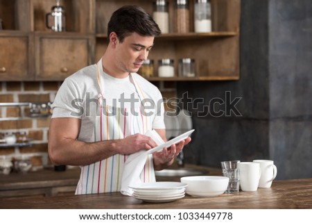 handsome man wiping plate with towel at kitchen