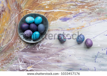 Painted chicken eggs in bowl and on stained background