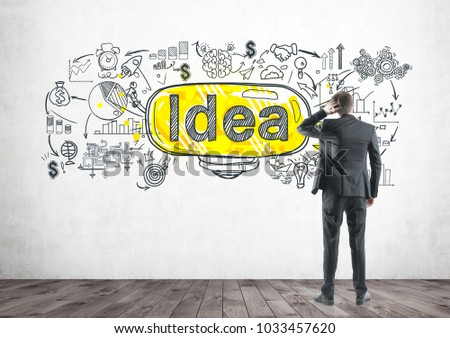 Rear view of a thoughtful well dressed businessman scratching his head. Yellow light bulbs on a concrete wall. An idea concept