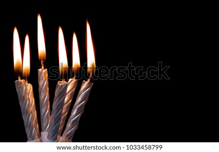 Six silver burning candles on black background with room for text