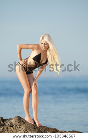 Girl at the sea. Attractive young blond woman in swimsuit posing on background of sea