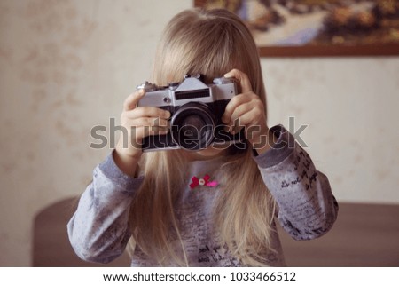 
child with long hair photographing on retro camera