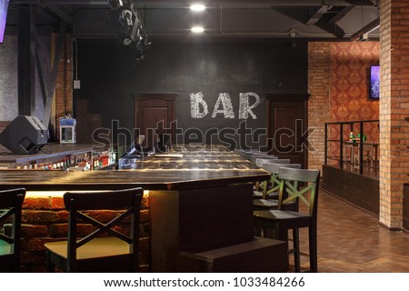 loft style bar interior with wooden countertop, bar chairs, bricks wall Royalty-Free Stock Photo #1033484266