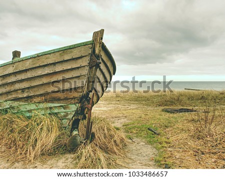 Wrecked wooden fisher boat. Broken abandoned boat in sand of sea bay. Wheatered wood and rusty meatal parts 