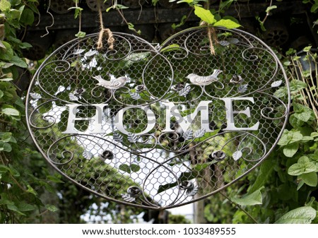 Decorative sign with text Home hangs over the entrance to the garden.