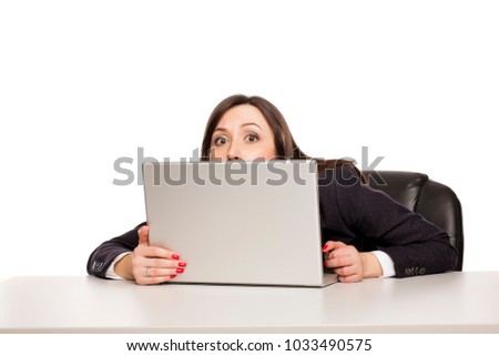 young business woman peeking behind her laptop