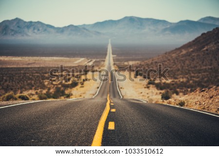 Classic panorama view of an endless straight road running through the barren scenery of the American Southwest with extreme heat haze on a beautiful sunny day with blue sky in summer Royalty-Free Stock Photo #1033510612