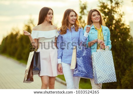 Beautiful girls with packages after shopping A picture of a group of happy friends shopping in the city. Girl walking around the city after shopping. good mood. Evening light. shopping concept