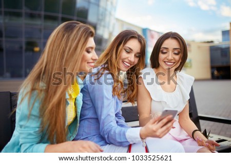 Beautiful girls with packages after shopping with phone. A picture of a group of happy friends shopping in the city. Girl walking around the city after shopping. Evening light. shopping concept