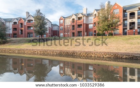 Mirror reflection of typical riverside apartment building complex at sunset in Irving, Texas, USA, wintertime. Panorama style
