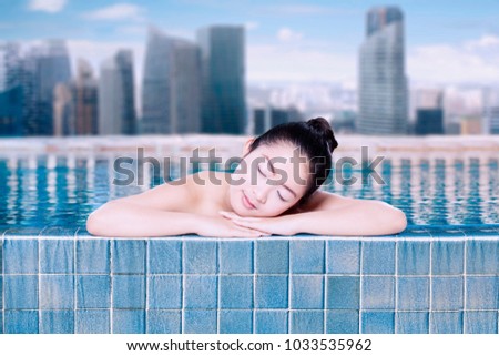 Picture of beautiful woman looks sleep during relaxing in the swimming pool. Shot with modern city background