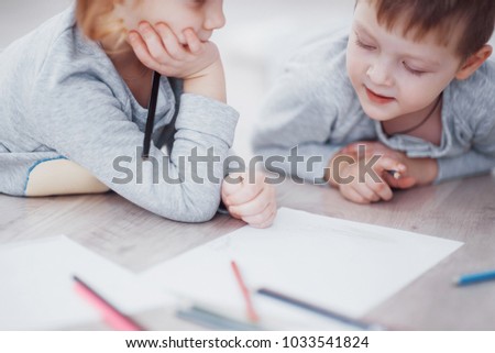 Children lie on the floor in pajamas and draw with pencils. Cute child painting by pencils.Hand of child girl and boy draw and paint with crayon. Close up view.