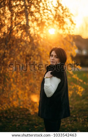 A young mother walks through the park in the golden autumn